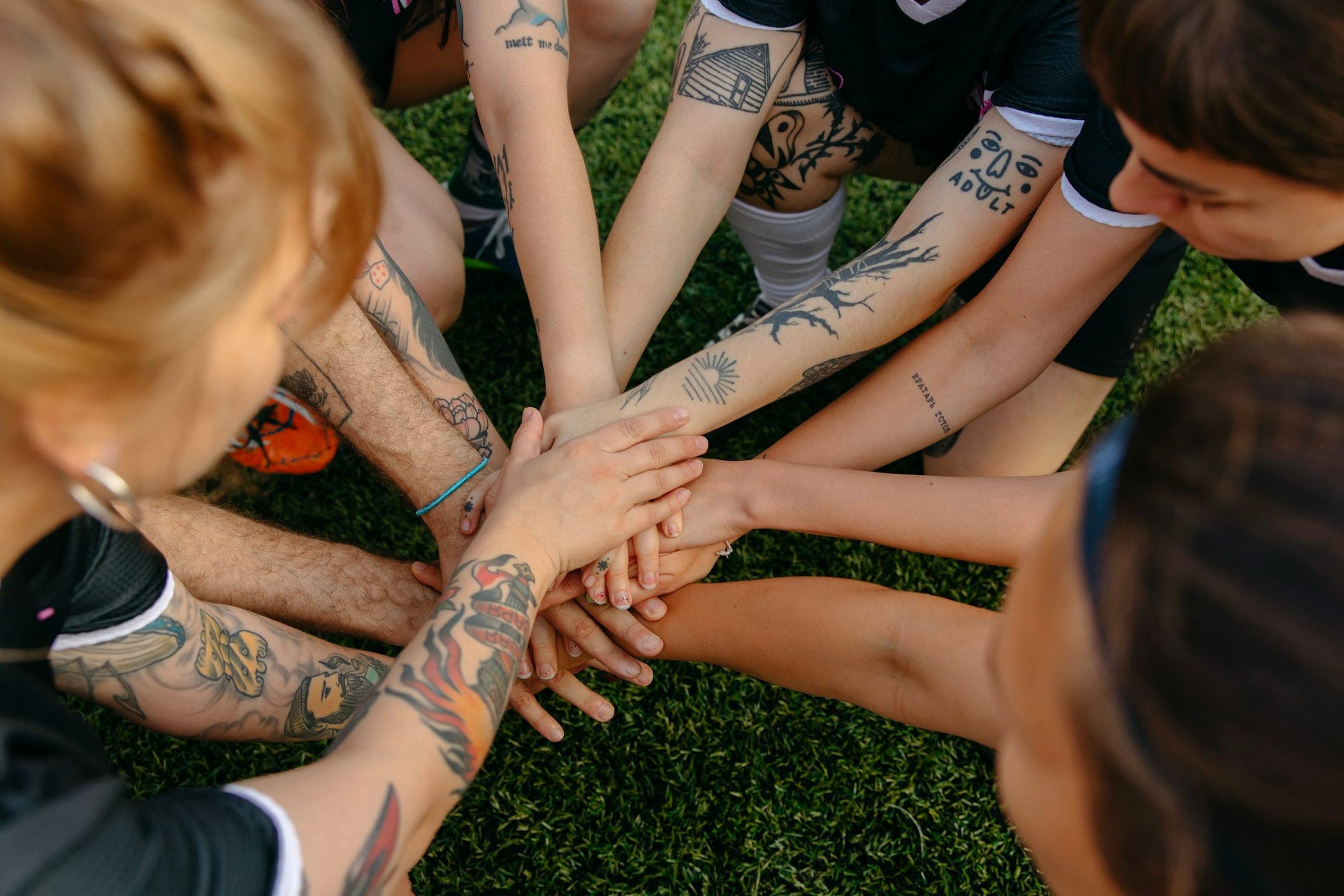 Players stacking their hands together in a team huddle on the pitch