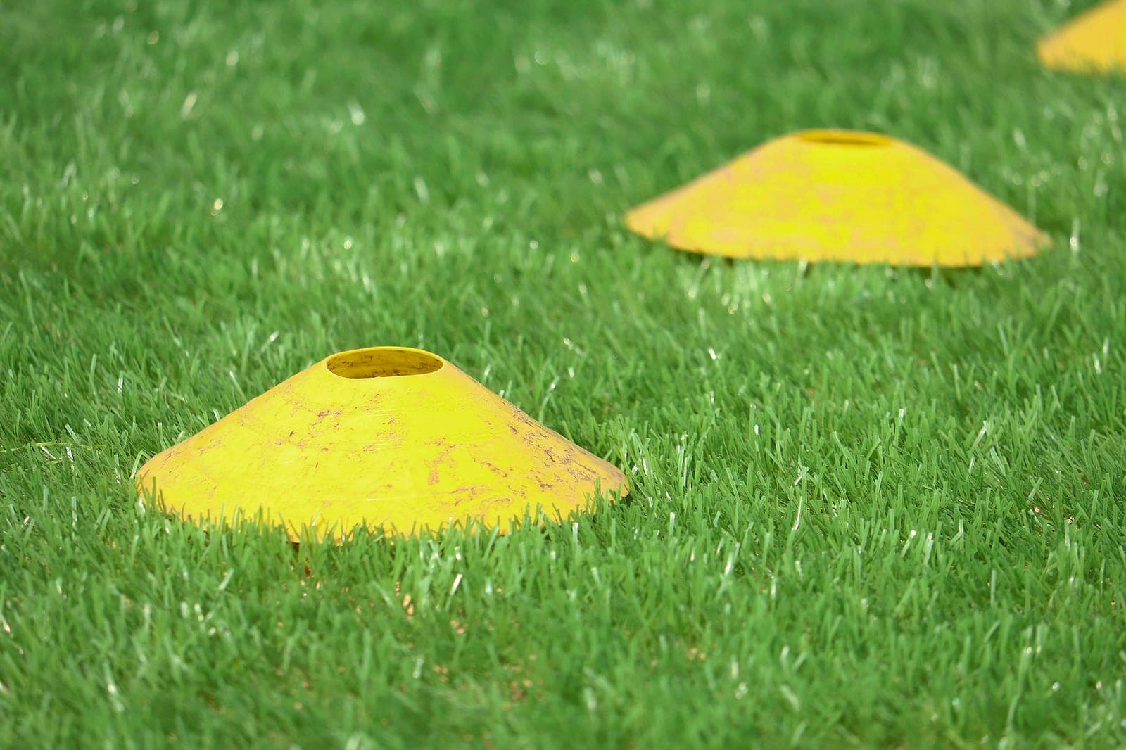 Yellow training cones laid out on green turf before a session